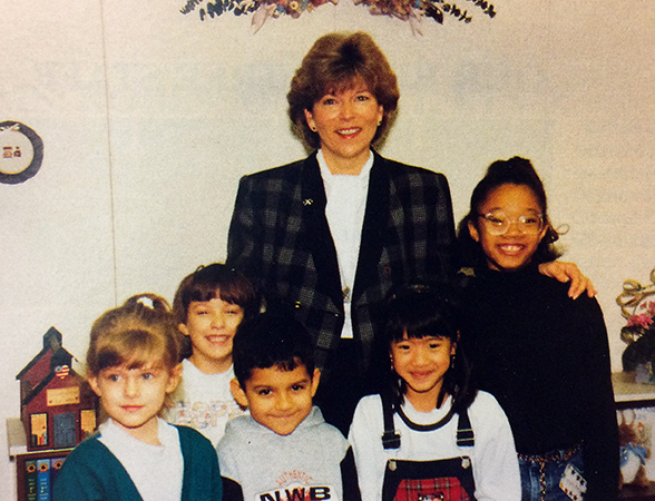 Color photograph of Principal Barker from our 1995 to 1996 yearbook. She is standing with a group of five smiling children. 