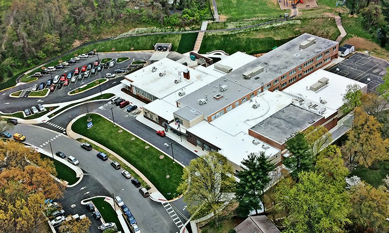 Color aerial photograph of Beech Tree Elementary School taken after the renovation was complete. All of the open spaces and courtyards between the wings of the building were enclosed to create classroom spaces. A parking lot has been added where the modular building once stood.