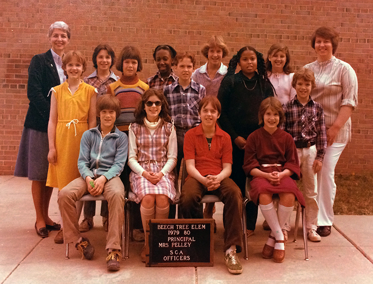 Color photograph of Principal Pelley posing with Beech Tree’s SCA officers from the 1979 to 1980 school year. 13 children are pictured, posed on the sidewalk in front of our building.