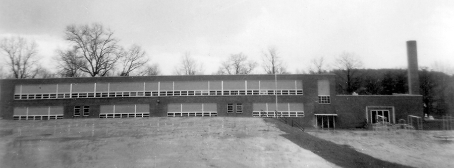 Black and white photograph of the front exterior of Willston Elementary School. The building is a two-story structure set on top of a hill. The steep terrain and small school site, less than five acres in size, contributed to the school’s closure. 